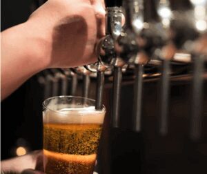 A person holding a beer mug under the keg tap